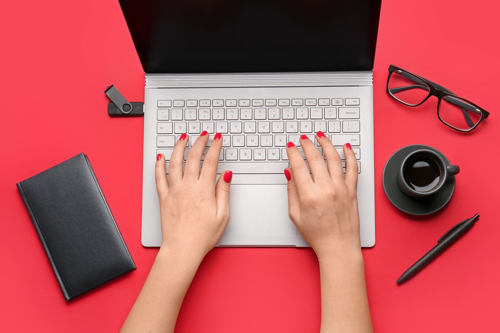 Hände mit rotem Nagellack tippen auf einem Laptop